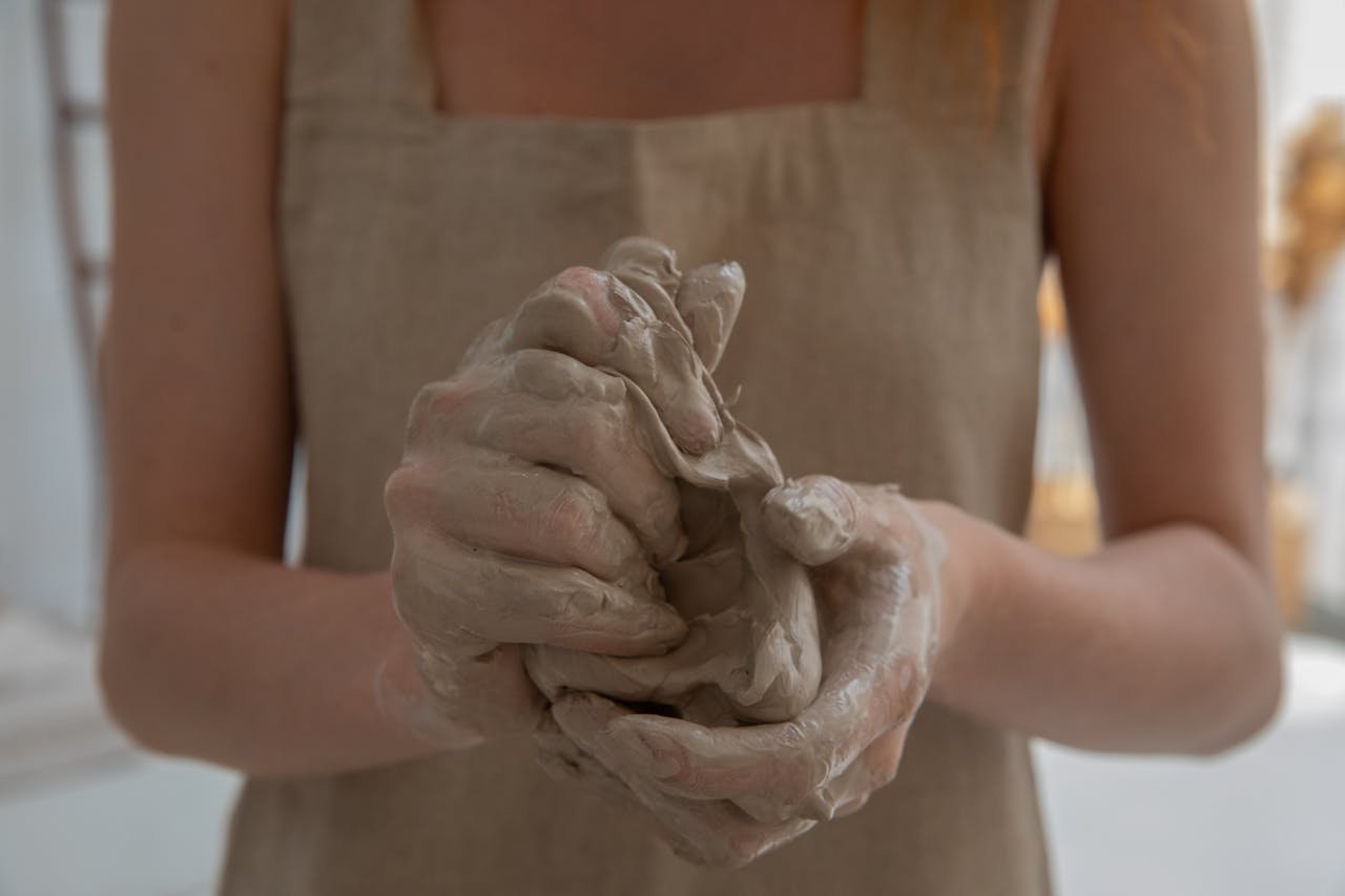 A craftswoman kneading clay in an indoor workshop, showcasing detailed craftsmanship.