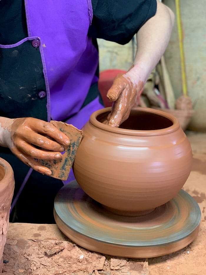 Close-up of hands shaping clay on a potter's wheel, showcasing artisan skills.